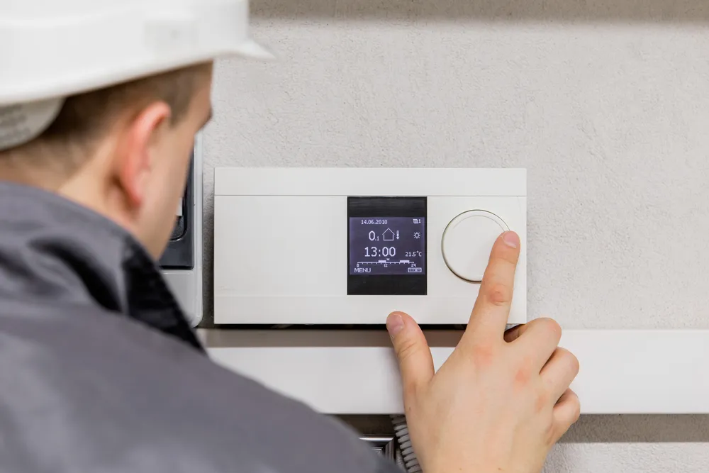 Technician adjusting modern heating system thermostat for optimal performance and energy efficiency.