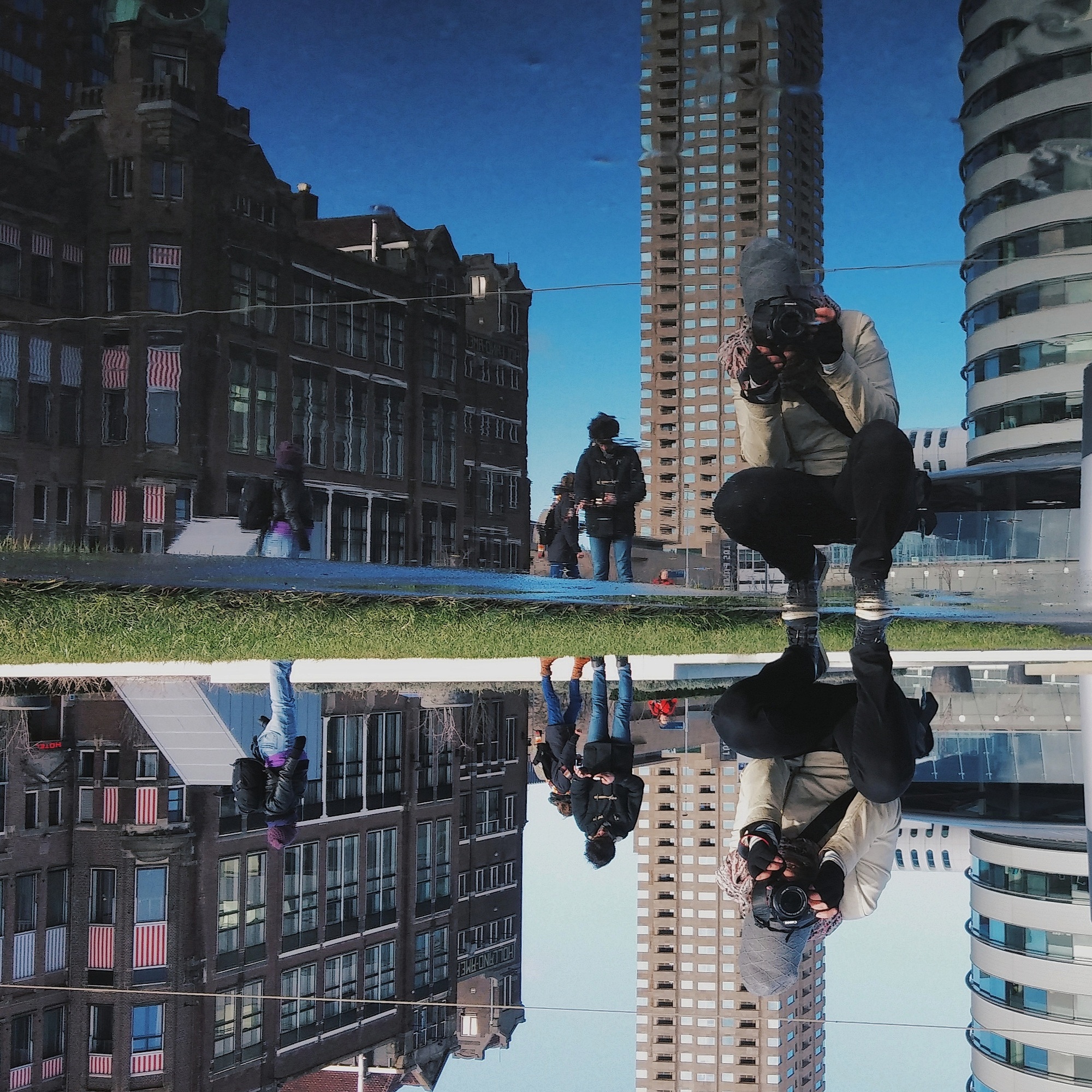 Reflection of buildings and people in water, creating a mirrored effect. Cityscape photography | Accurate Air