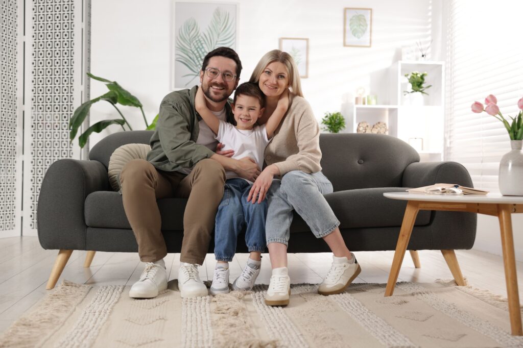 Happy family portrait on couch in living room. Air quality impacts family health and comfort. Air purification service benefits | Accurate Air