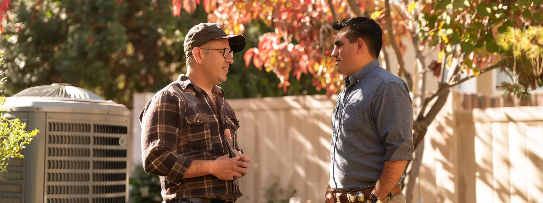 Two HVAC technicians discussing maintenance tips outdoors near an air conditioning unit, surrounded by autumn foliage in Tempe, Arizona.