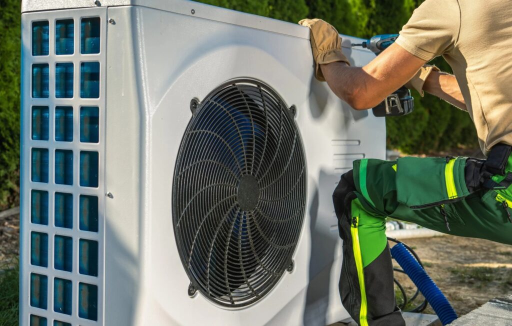 An HVAC technician fitting the casing of an outdoor heat pump unit.