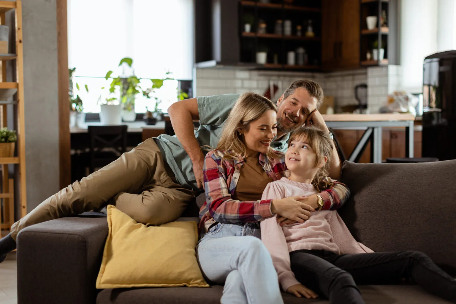 A family relaxing together on a sofa in a warm, comfortable living room.
