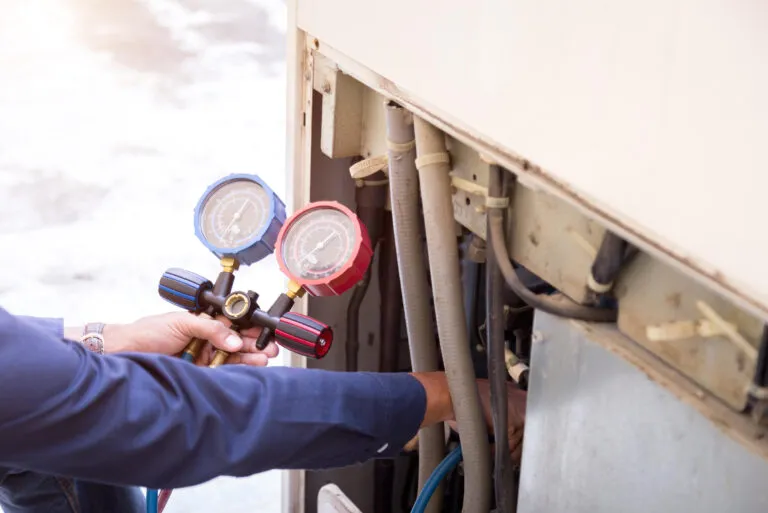 Refrigerant manifold gauges connected to an air conditioning system during a service call.